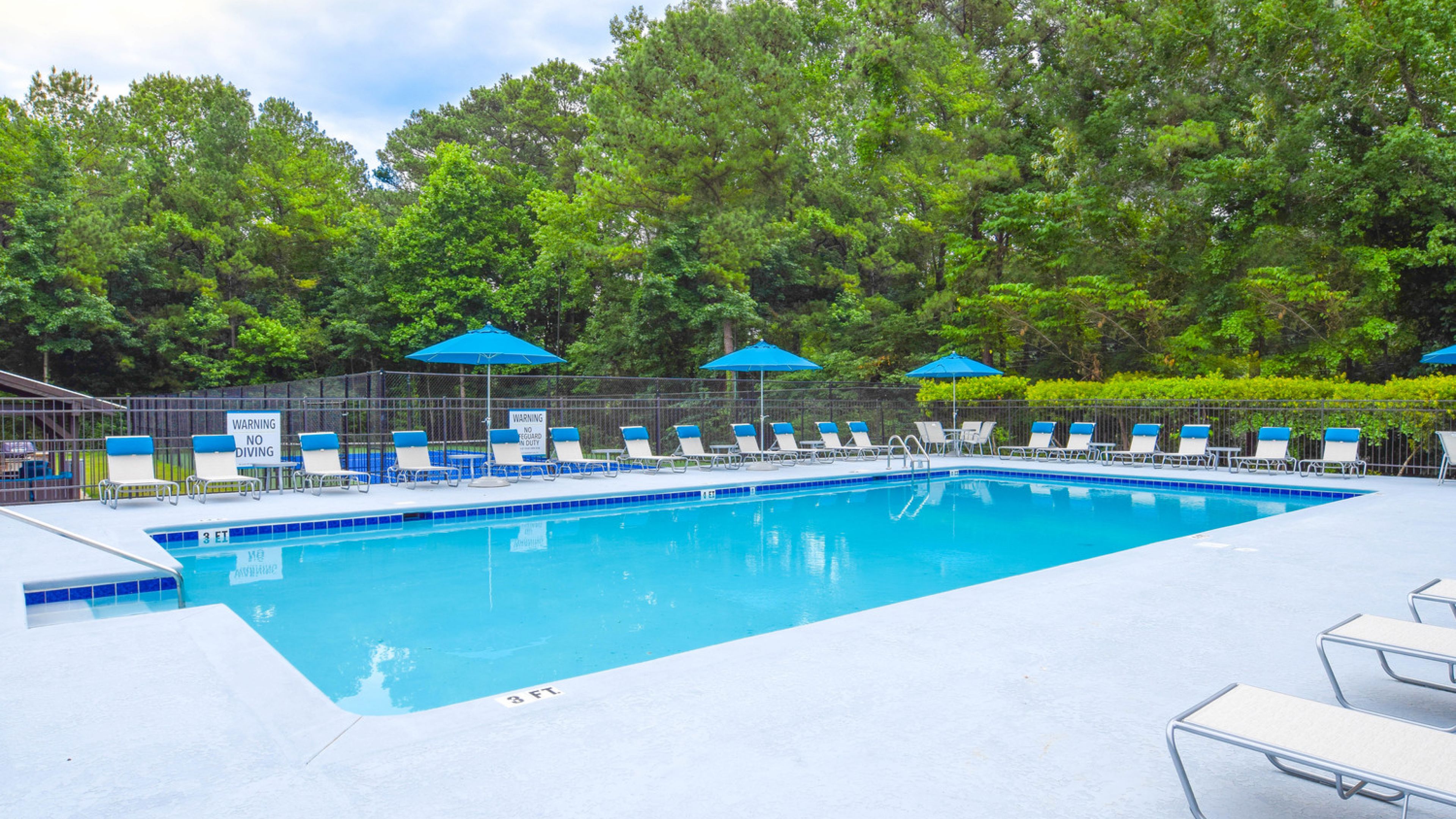 Hawthorne at Wisteria outdoor pool with surrounding seating, tables, and umbrellas
